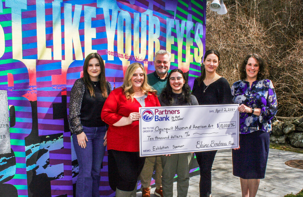 Group stands in front of colorful art wall for Ogunquit Museum of Art donation from Partners Bank. Group is holding a large Partners Bank check for $10,000.