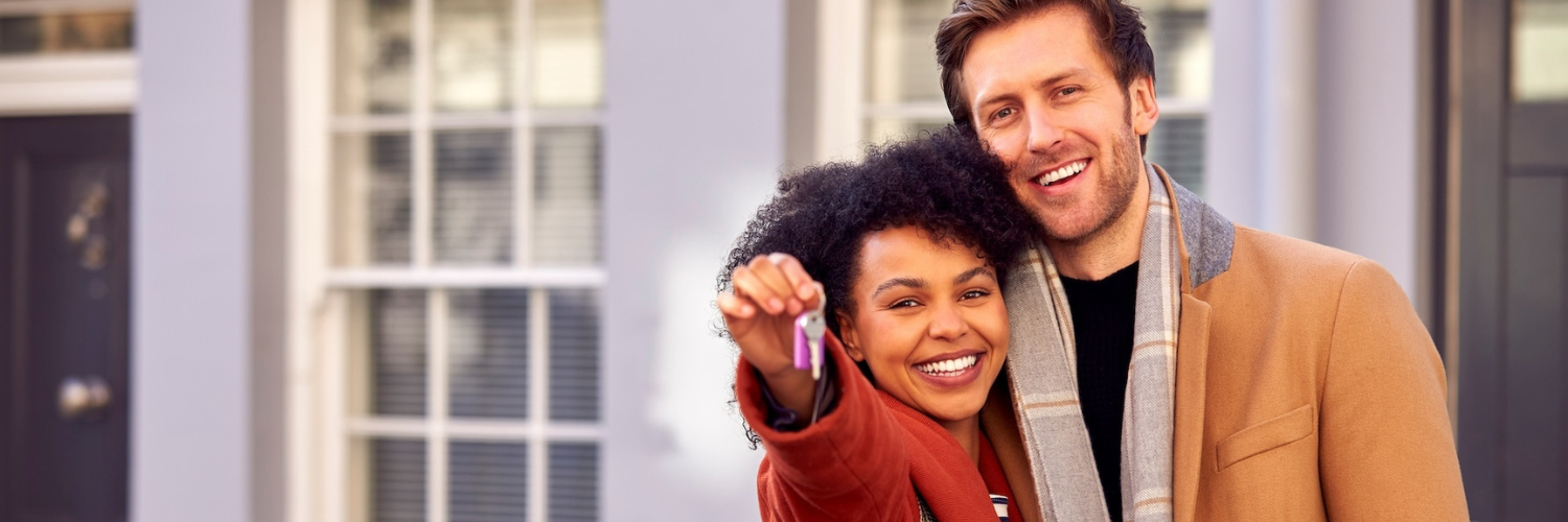 Two people happy holding keys to new house